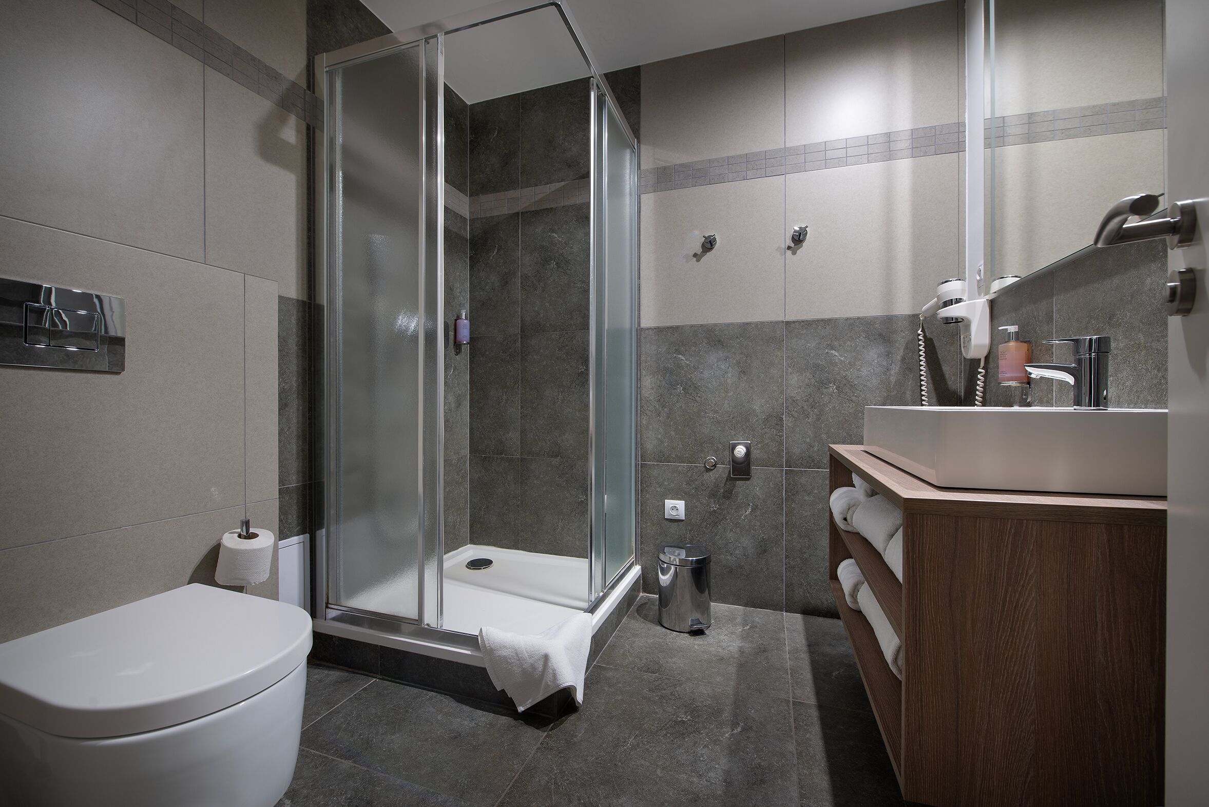Un baño moderno con cabina de ducha de vidrio, inodoro y tocador con espejo.