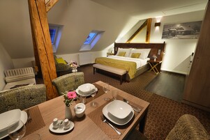 Un dormitorio con una cama grande, un tragaluz, una zona de comedor con una mesa dispuesta para dos personas y un ambiente acogedor.