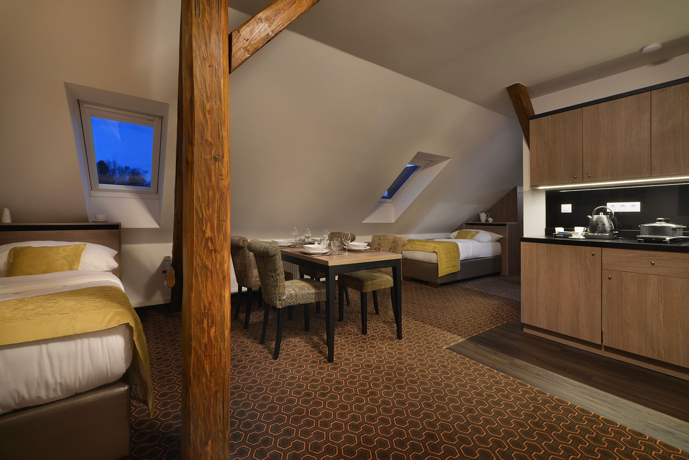 Une chambre d’hôtel moderne dotée d’un coin repas, d’une kitchenette et d’une grande fenêtre offrant une vue dégagée.