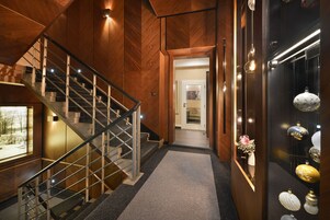 Un interior de madera con una escalera, un pasillo y una exhibición de objetos decorativos.