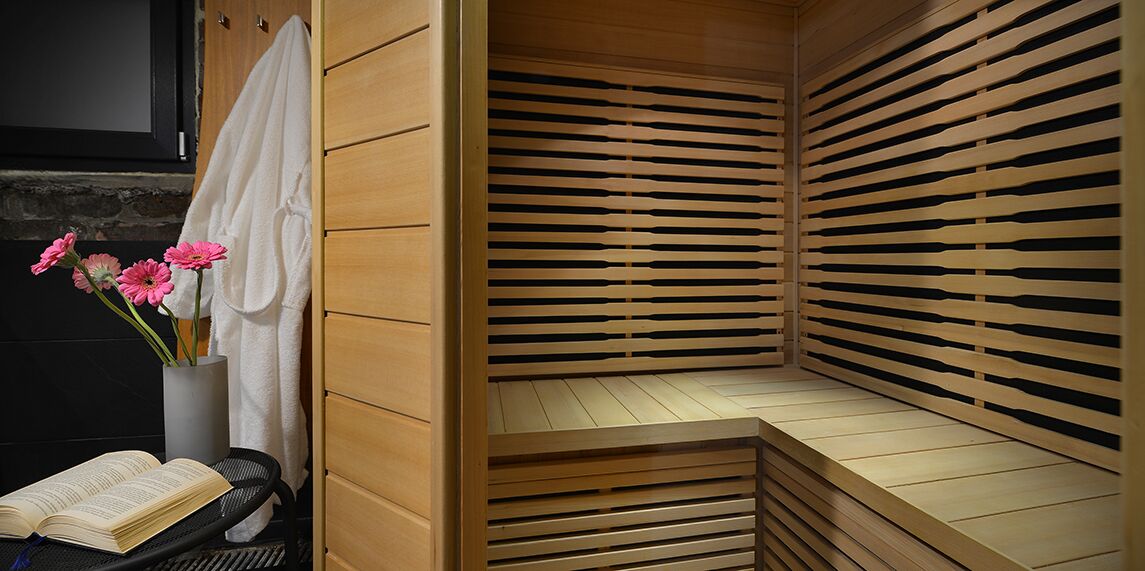 Een sauna met houten latten, een handdoek en een boek op een stoel.