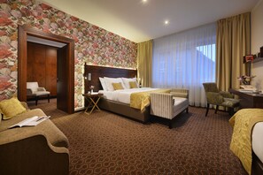 A hotel room with a large bed, a sitting area with a chair, a desk, and a wardrobe. - Vysocina Design Apartments (Hlinsko)