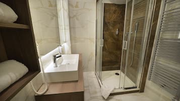 A modern bathroom with a glass-enclosed shower, a white sink, and a wooden vanity.