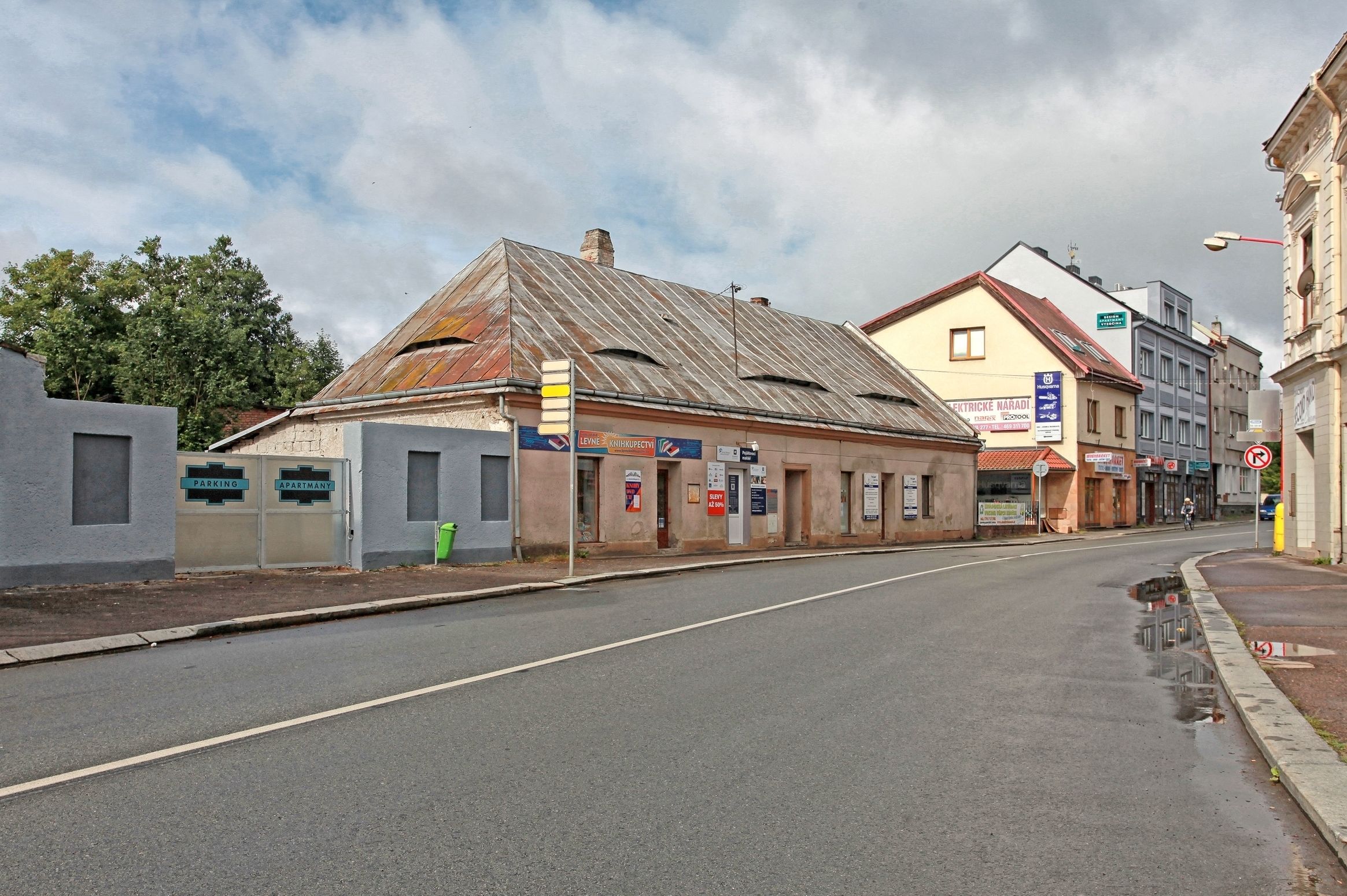 A street with a building that has a sign for a parking area and an apartment.