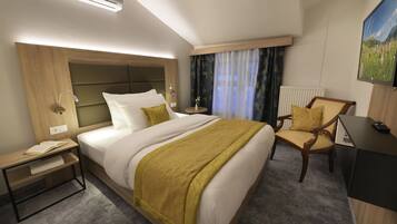 Una habitación de hotel con cama, mesita de noche, silla y escritorio con computadora.