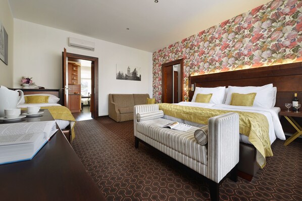 A hotel room with a bed, a sofa, a desk with a chair, and a small table. - Vysocina Design Apartments (Hlinsko)
