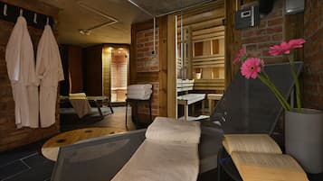 A spa room with a massage table, towels, a wooden chair, and a glass partition.