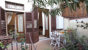 A courtyard with a white table and chairs, surrounded by potted plants and a metal fence. - Flospirit - Bellini (Florence)