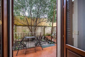 A courtyard with a metal table and chairs, a small staircase, and a tree.