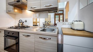 A modern kitchen with a gas stove, oven, sink, and a toaster. - Flospirit - Bellini (Florence)