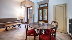 A dining area with a round wooden table, red cushioned chairs, a wooden bench, and a beige door. - Flospirit - Bellini (Florence)