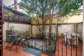 A courtyard with a tree, a metal fence, and two tables. - Flospirit - Bellini (Florence)