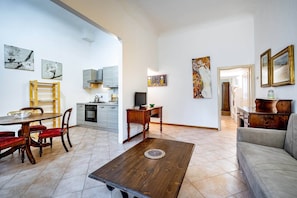 A spacious living area with a dining table, sofa, and kitchen in the background.