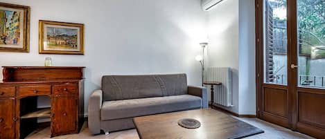 Una sala de estar con un sofá, una mesa de centro, un escritorio de madera y dos cuadros en la pared.