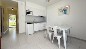 Cuina moderna amb armaris blancs, microones i ventilador de sostre.