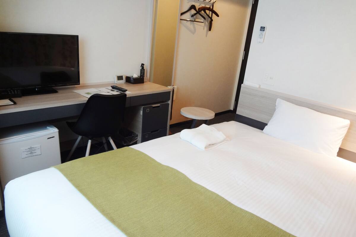 Une chambre d’hôtel équipée d’un lit, d’un bureau, d’une chaise, d’une télévision et d’une petite table.