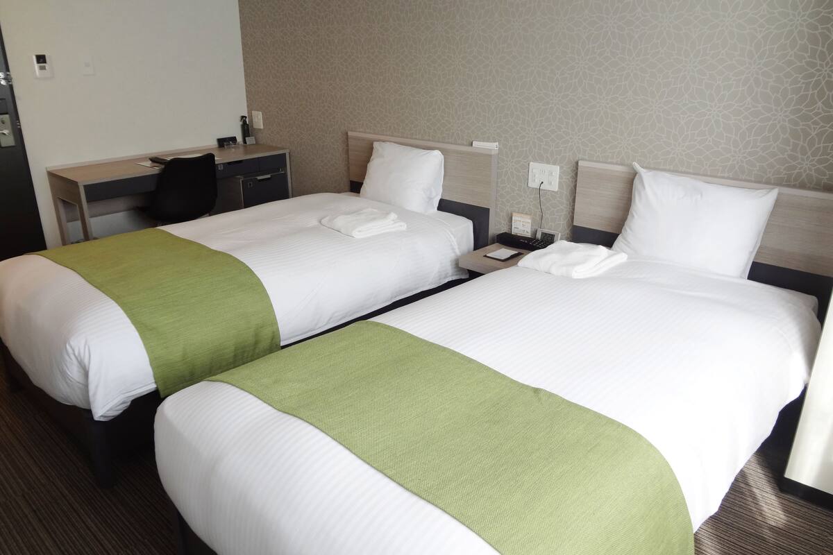 Une chambre d’hôtel avec deux lits, un bureau et une chaise.