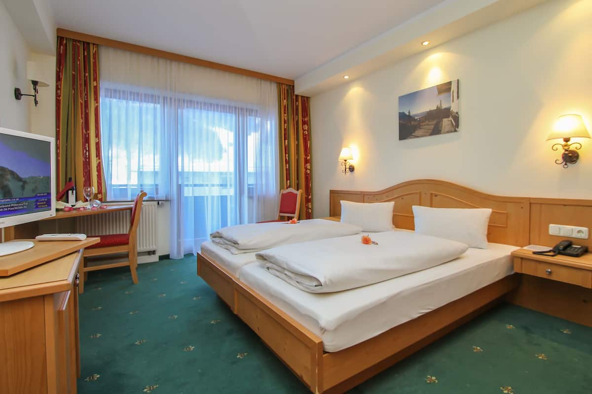 A hotel room with a bed, desk, chair, and a television.