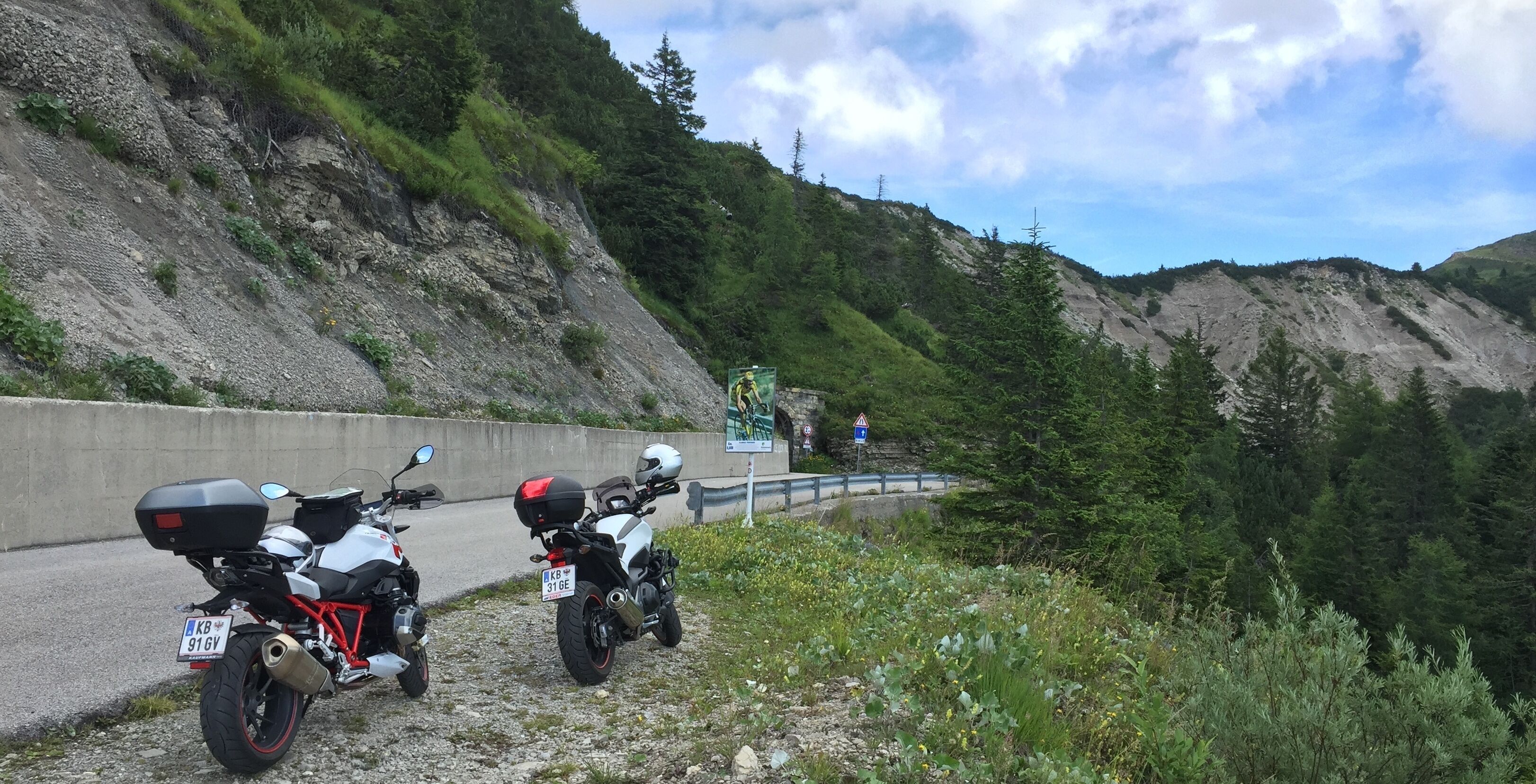 Dos motocicletas estacionadas al borde de una carretera, con montañas al fondo.