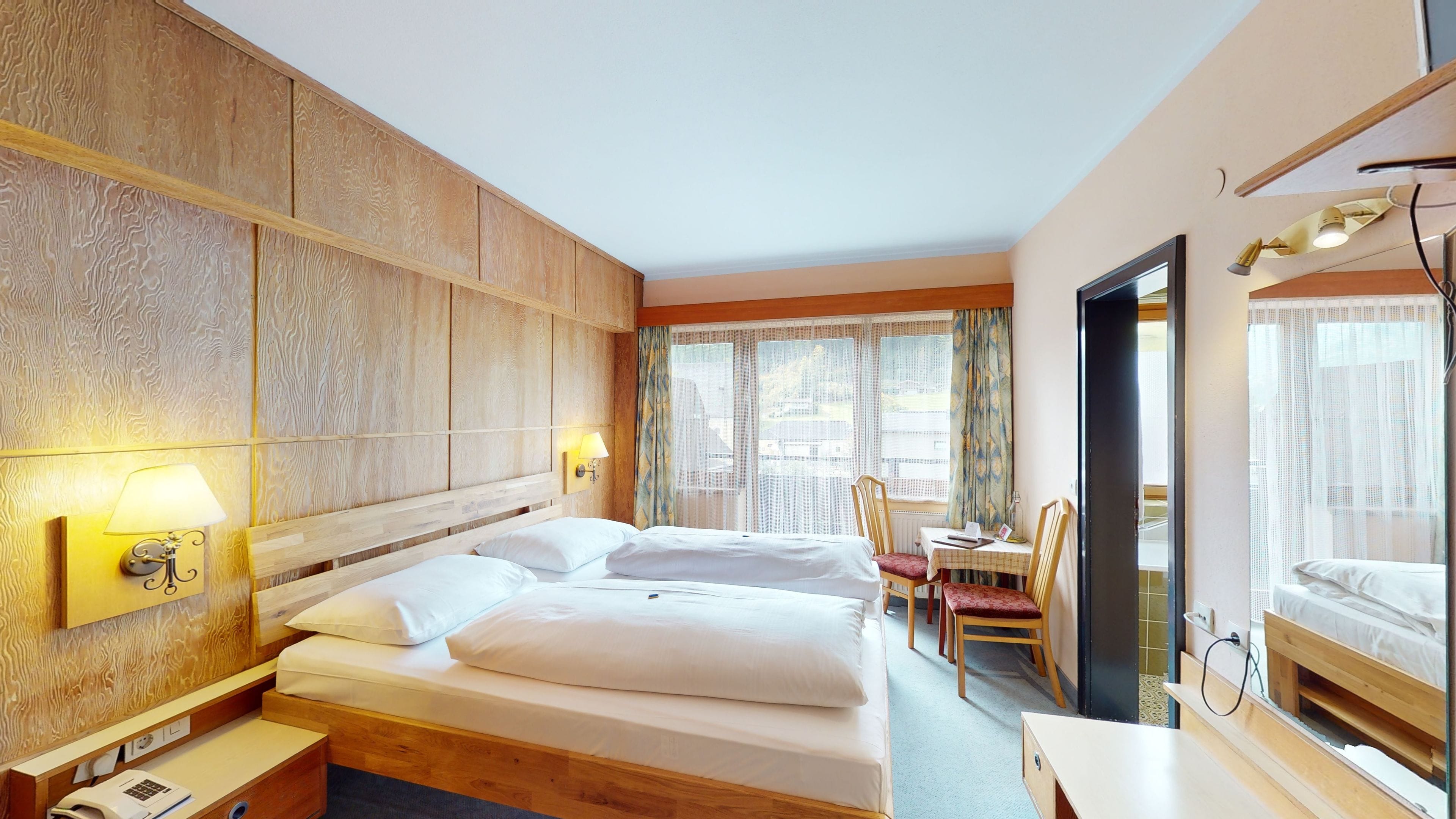 Ein Hotelzimmer mit einem großen Bett, einem Schreibtisch, einem Stuhl und einem Spiegel.