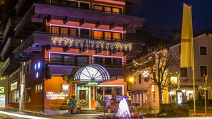Un hotel con una entrada destacada, varios balcones y luces festivas.