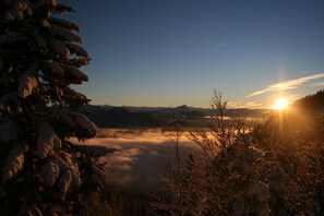 A snowy landscape with a mountain range in the background and the sun setting on the horizon. - Hotel Tiroler ADLER Bed & Breakfast (Waidring)