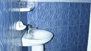 Un baño con lavamanos blanco, un espejo y un perchero para toallas.