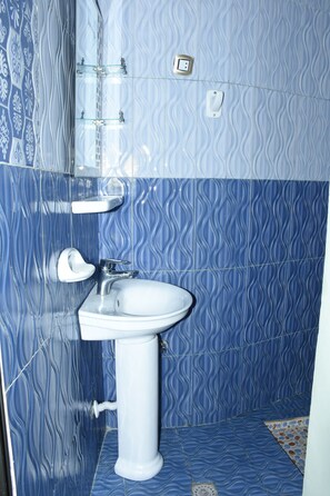 Un baño con lavamanos blanco, un espejo y un perchero para toallas.