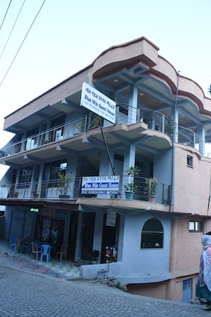 Un edificio de varios pisos con balcones, un letrero que dice 'Blue Nile Guest House' y asientos al aire libre.