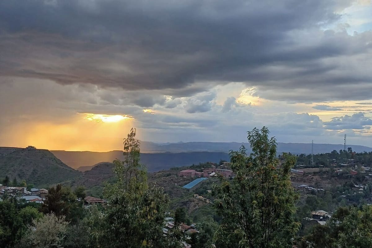 Paisaje montañoso con atardecer, edificios y cielo despejado.