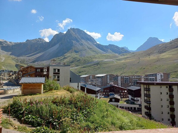 A residential area with modern buildings, a small wooden structure, and a mountainous backdrop.