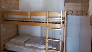 A bunk bed with a ladder, a small shelf, and a hook for hanging items.