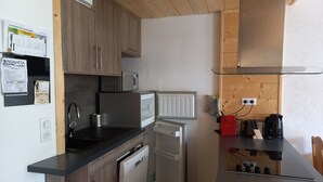 A compact kitchen with wooden cabinets, a microwave, a refrigerator, a dishwasher, and a coffee maker.
