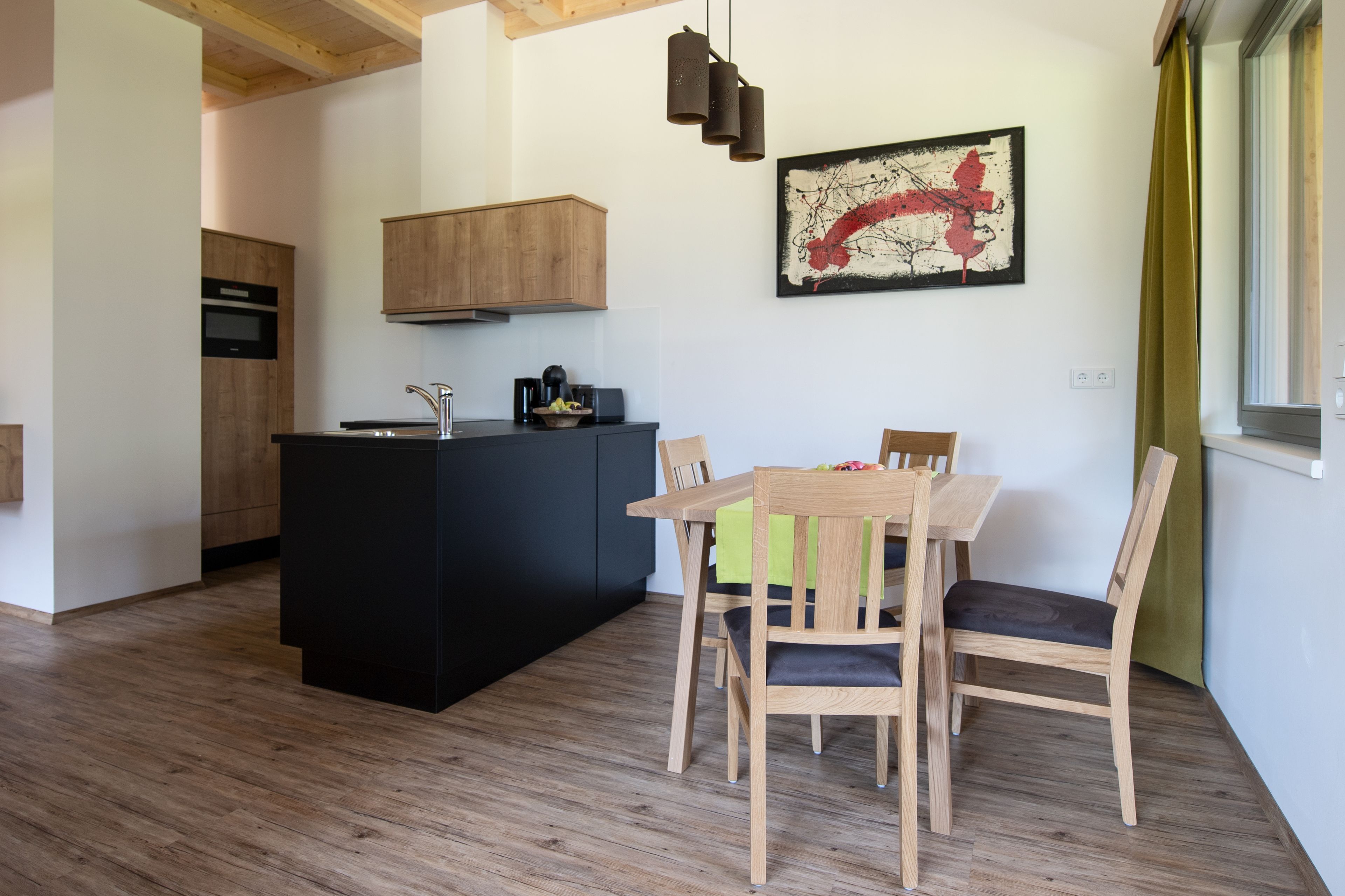 Una cocina moderna con armarios de madera, encimera negra y comedor con mesa y sillas de madera.