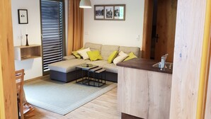 A cozy living area with a sofa, a small coffee table, and a wooden ceiling.