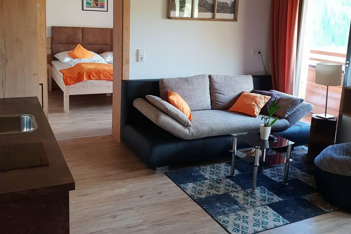 A cozy living room with a sofa, a bed, and a dining area.