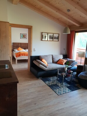 A cozy living room with a sofa, a bed, and a dining area.