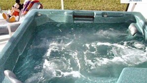 Un bain à remous rempli d’eau, une télécommande et deux peluches posées sur le bord.