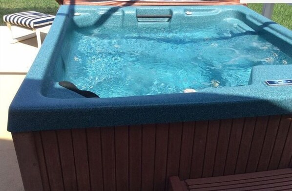 Un jacuzzi con revestimiento de madera y un panel de control en el lateral.