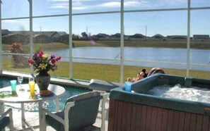 Un jacuzzi y una piscina con vistas a un lago y casas al fondo.