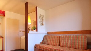 A small, cozy room with a wooden bench, a mirror, and a small table with a lamp.