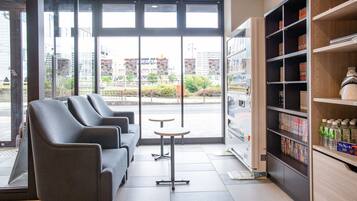 A modern interior with seating, a vending machine, and a view of the outside.