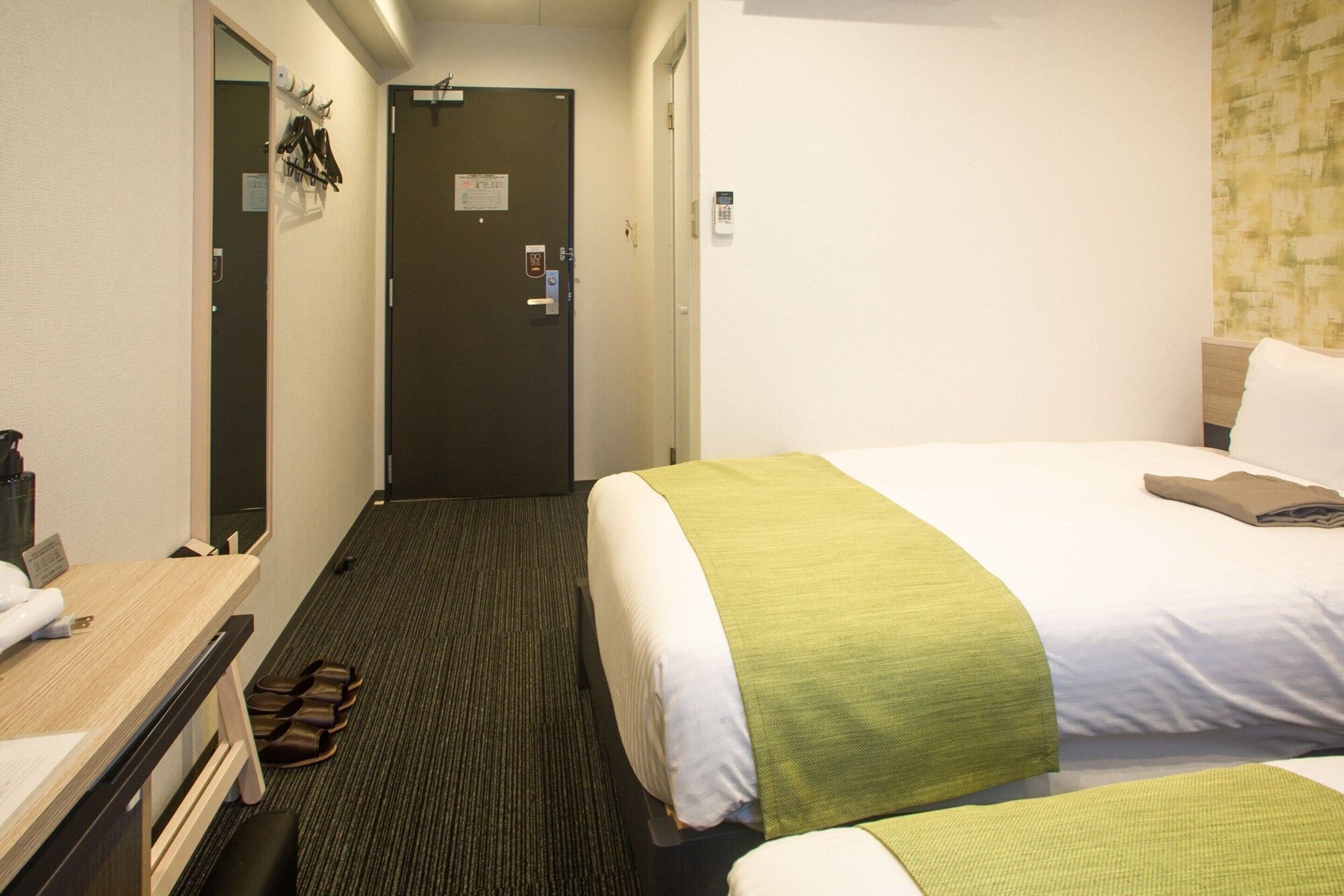 A hotel room with a bed, a desk, and a mirror.