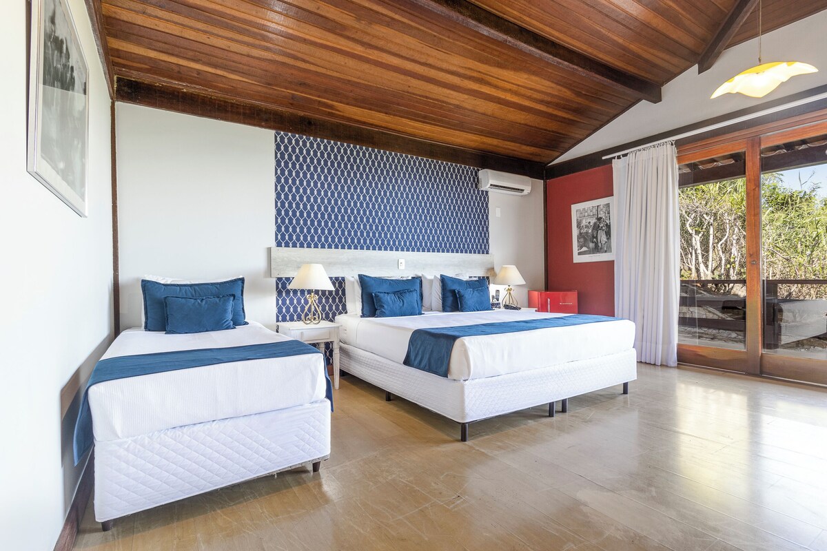 Habitación de hotel con dos camas, techo de madera, pared con diseño y un ventanal con vistas.