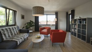 Una sala de estar moderna con un sofá, dos sillones, una mesita de centro y una estantería.