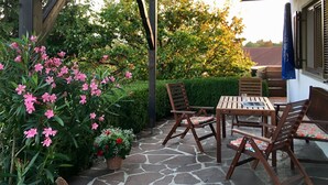 Un patio al aire libre con suelo de piedra, muebles de madera y plantas en macetas.