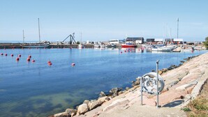 A marina with boats docked, a rocky shoreline, and a clear sky.