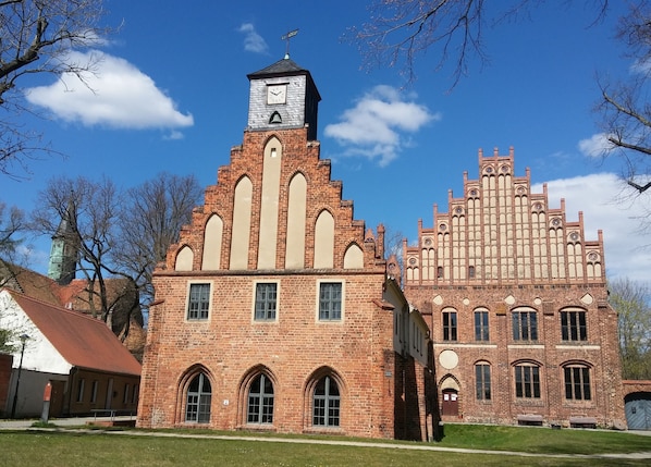 A historic building with a clock tower and arched windows, featuring a mix of brick and stone construction. - Hotel Alte Försterei Kloster Zinna (Jueterbog)