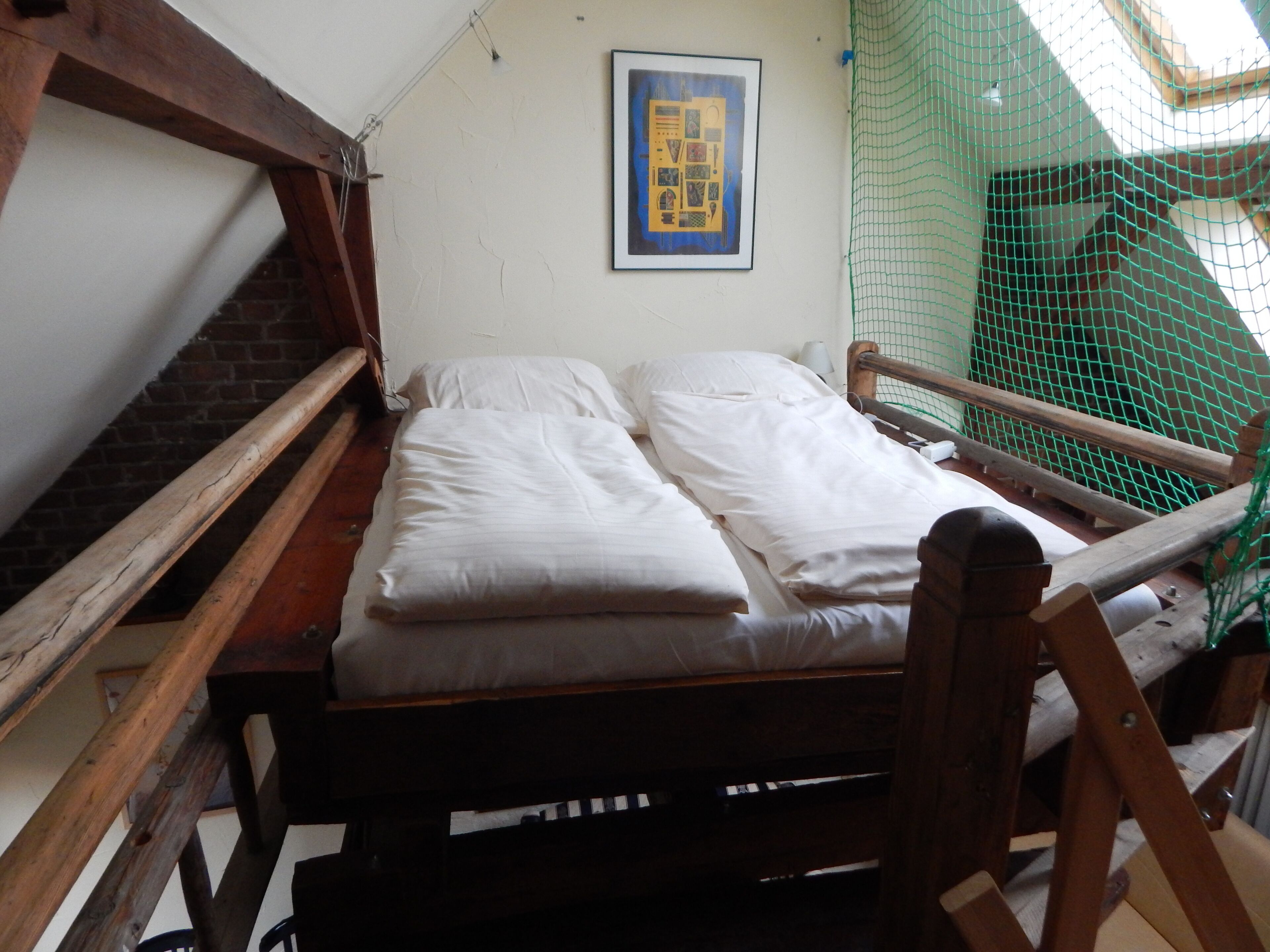Ein kleiner, rustikaler Raum mit einem Holzbett, einer Ziegelwand und einer grünen Netzhaltung.