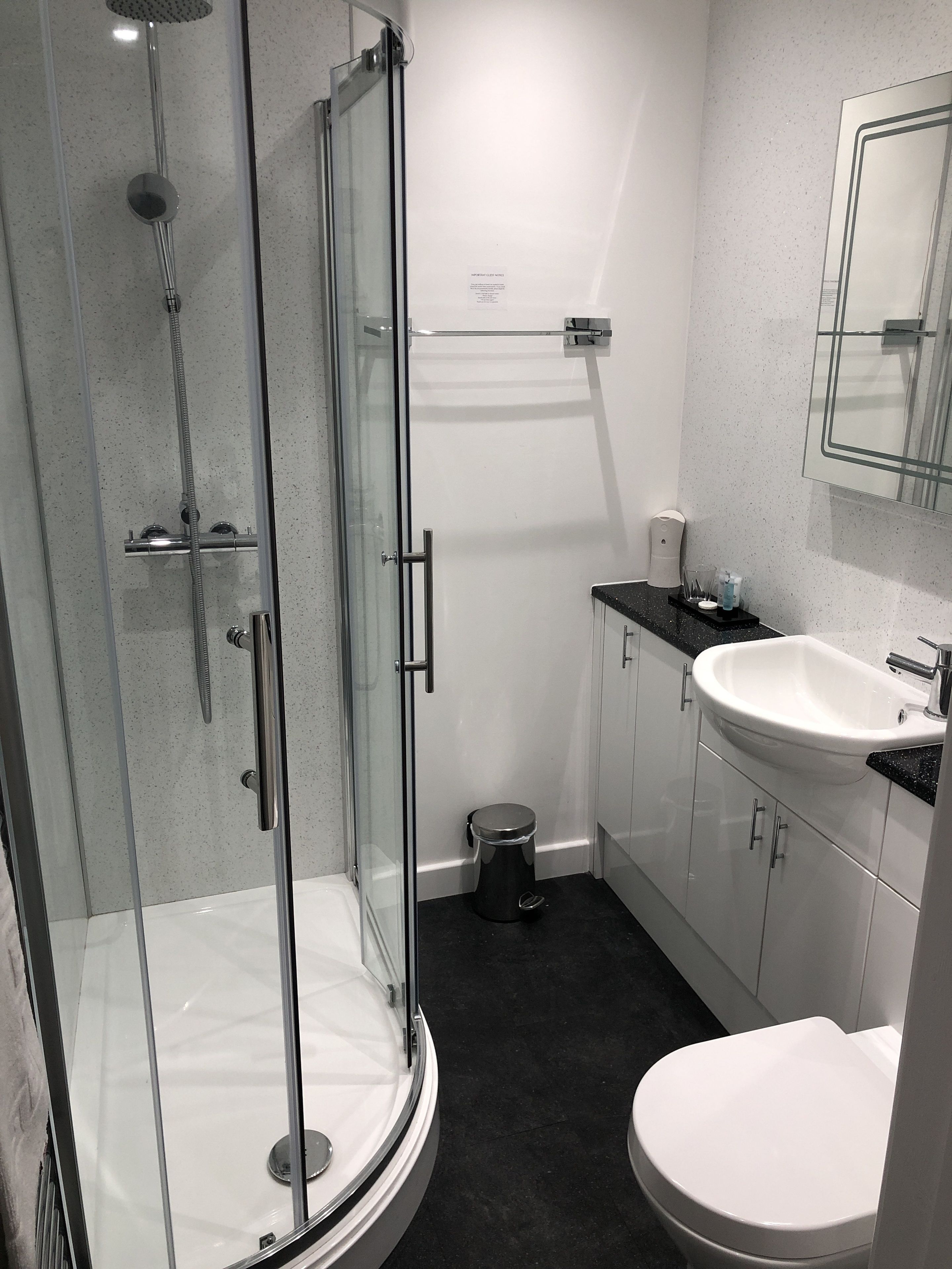 Ein modernes Badezimmer mit einer Duschkabine, einer weißen Toilette und einem Waschbecken mit schwarzer Arbeitsplatte.